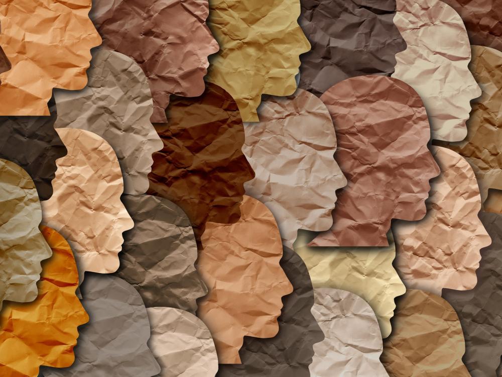 Silhouettes of diverse human profiles made of crumpled paper in various skin tones, representing diversity and unity.