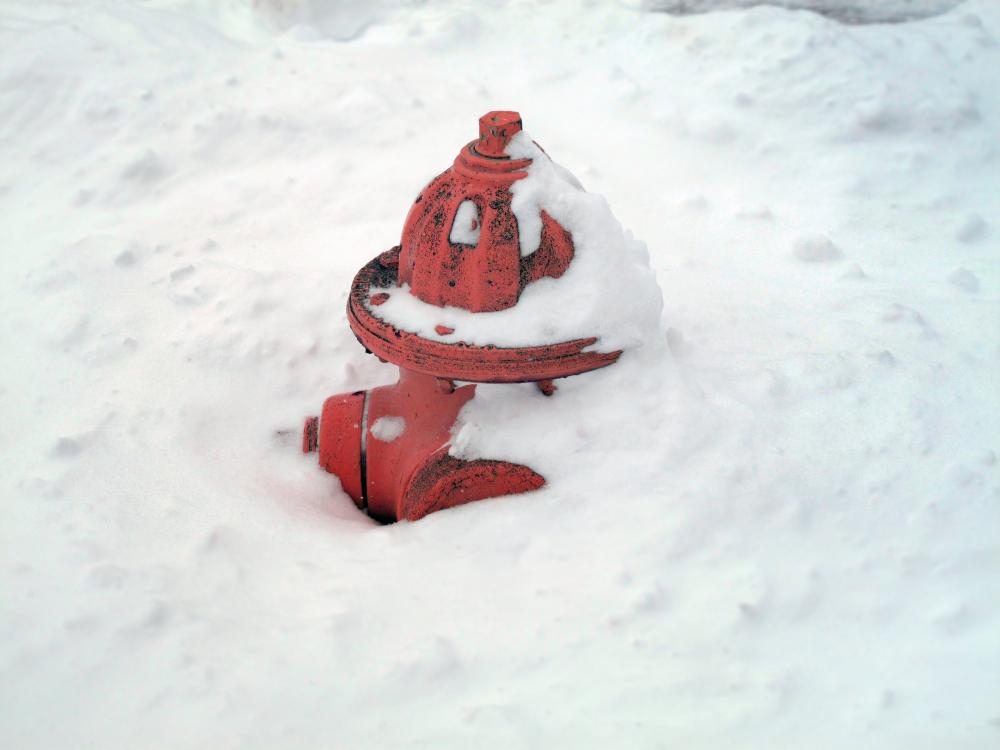 A red fire hydrant partially buried in snow, highlighting the need for accessibility during winter weather conditions.