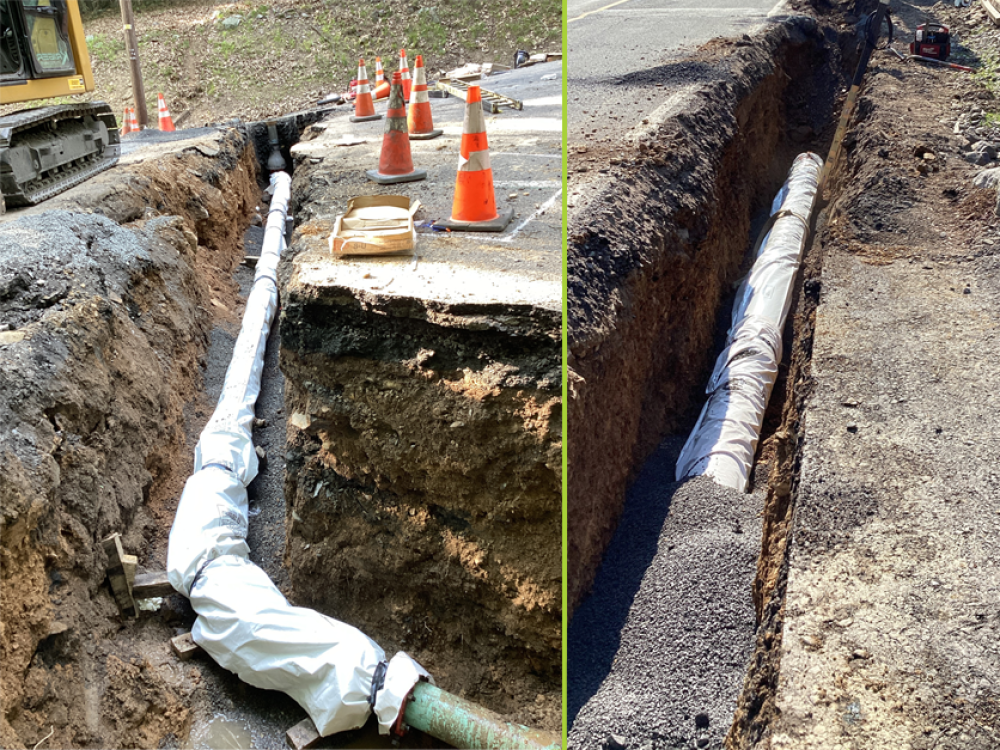 Image of a trench with underground pipework under construction, partially wrapped and secured. Traffic cones line the trench edges.