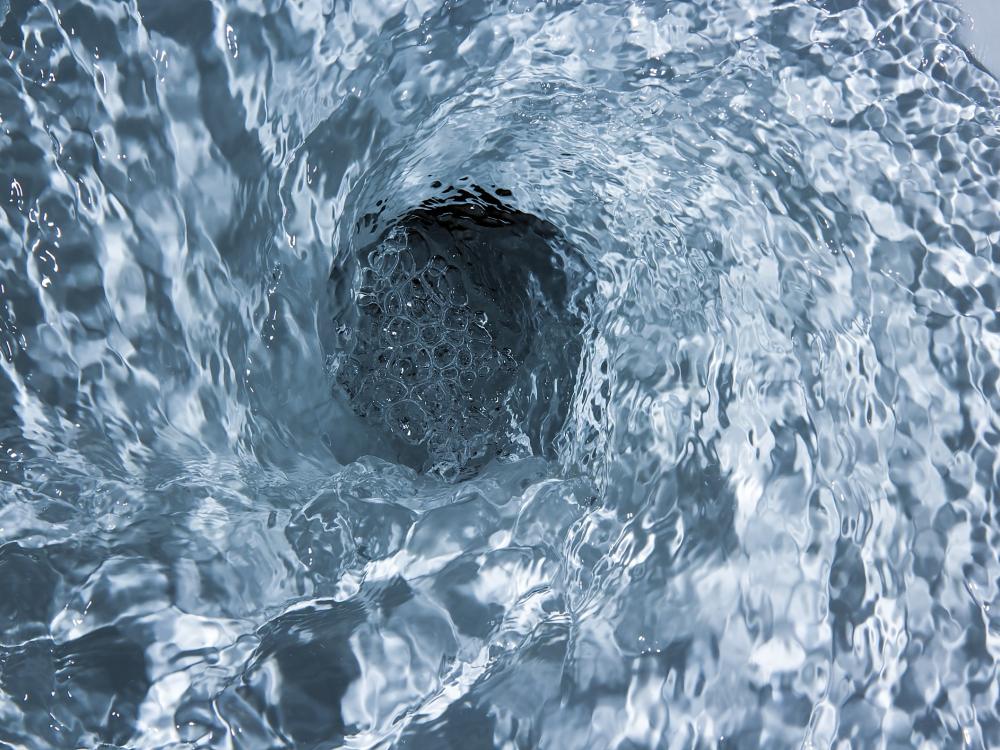 Close-up of water swirling down a drain, creating a whirlpool effect, symbolizing the flow of water and drainage.