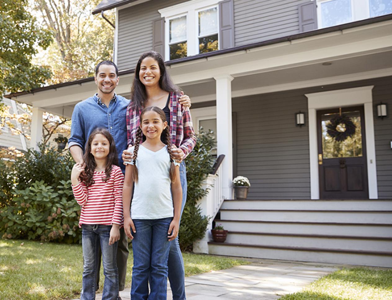 Couple with two children standing in front of house