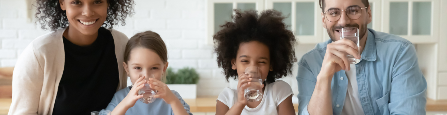 Family drinking glasses of water at kitchen island 