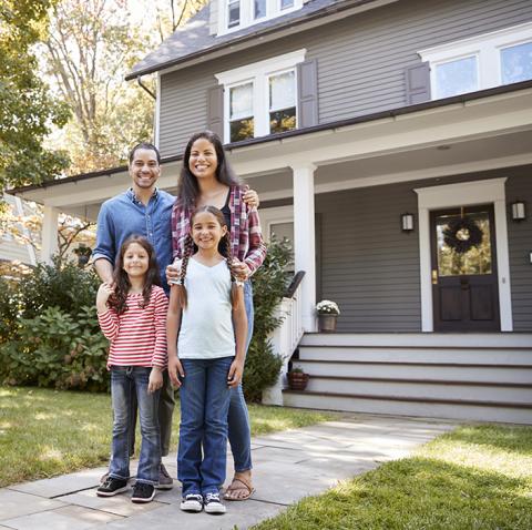 Couple with two children standing in front of house