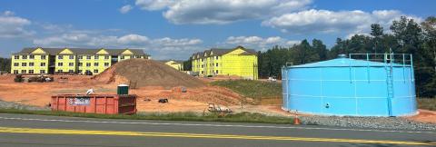 A blue water storage tank to the right, next to a construction site with apartments under construction in the distance. 